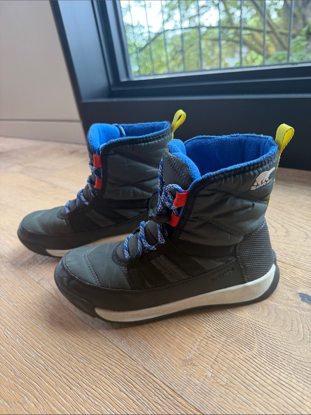 Gently used; Sorel Kids Black Winter Boots with Blue Lining and Yellow Pull Tabs